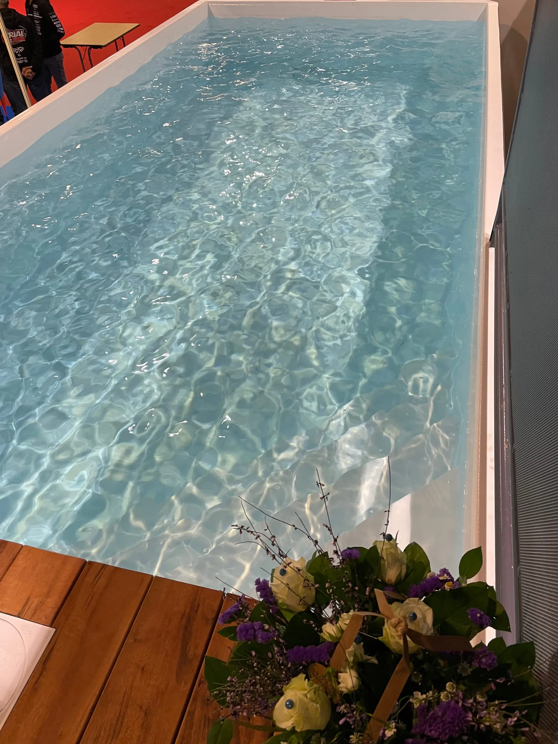 Vue plongeante sur le bassin d'une piscine en benne Trident Piscine Mobile, eau cristalline et terrasse en bois