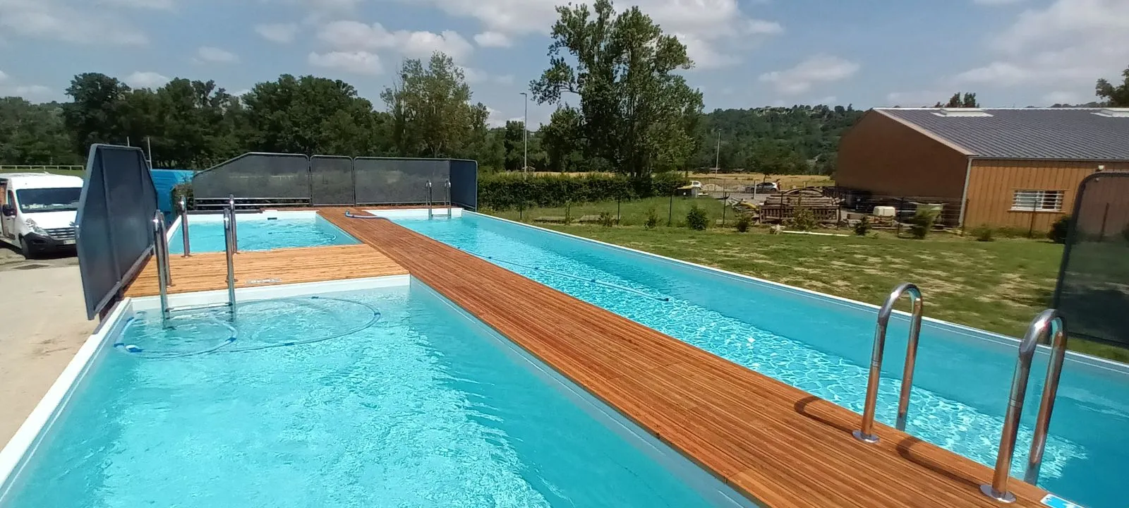 Double piscine container mobile Trident Piscine installée en extérieur, terrasse en bois et eau turquoise, vue panoramique