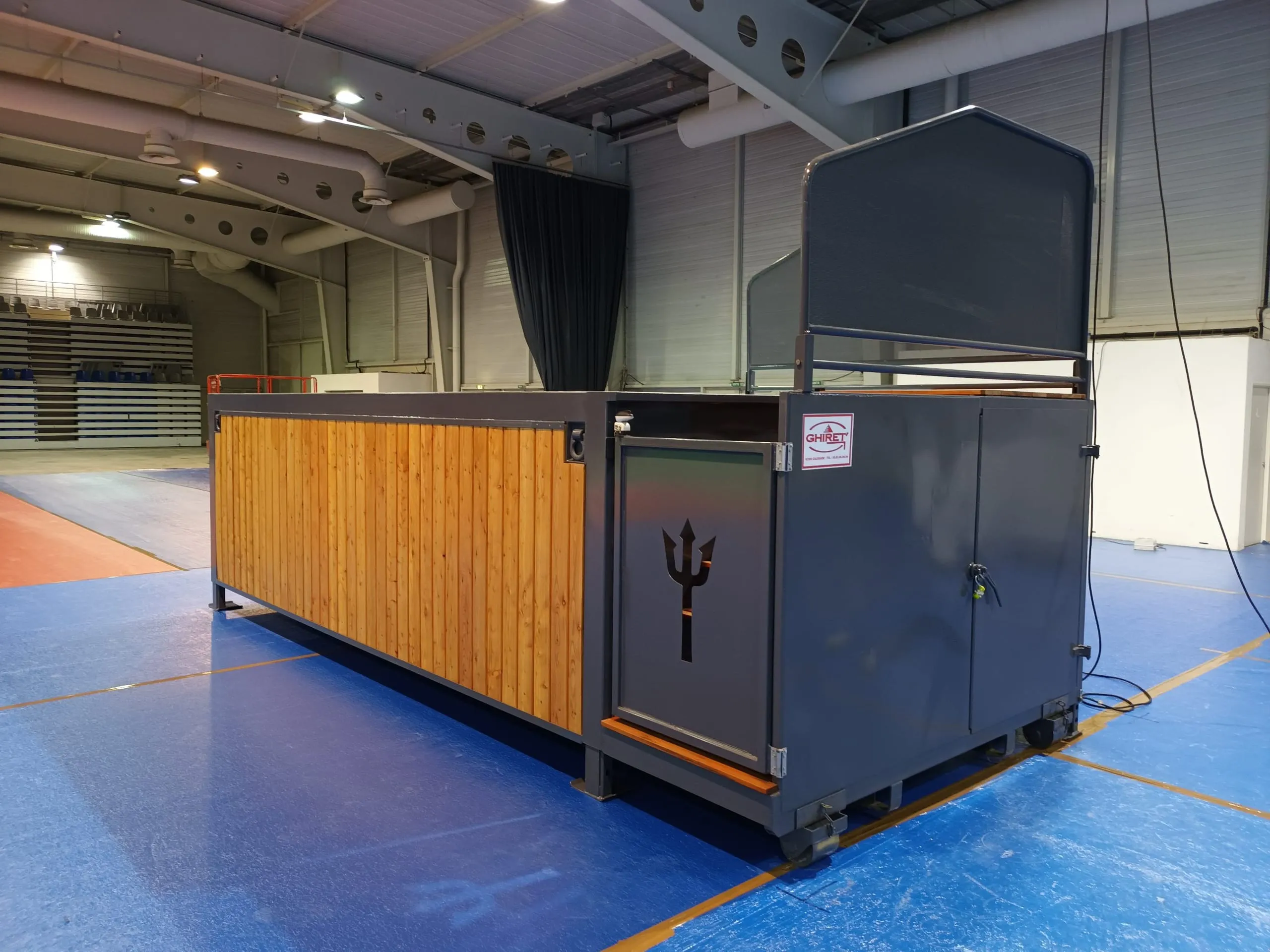 Piscine container mobile Trident Piscine vue de trois quarts, logo trident sur le flanc, structure anthracite et bois