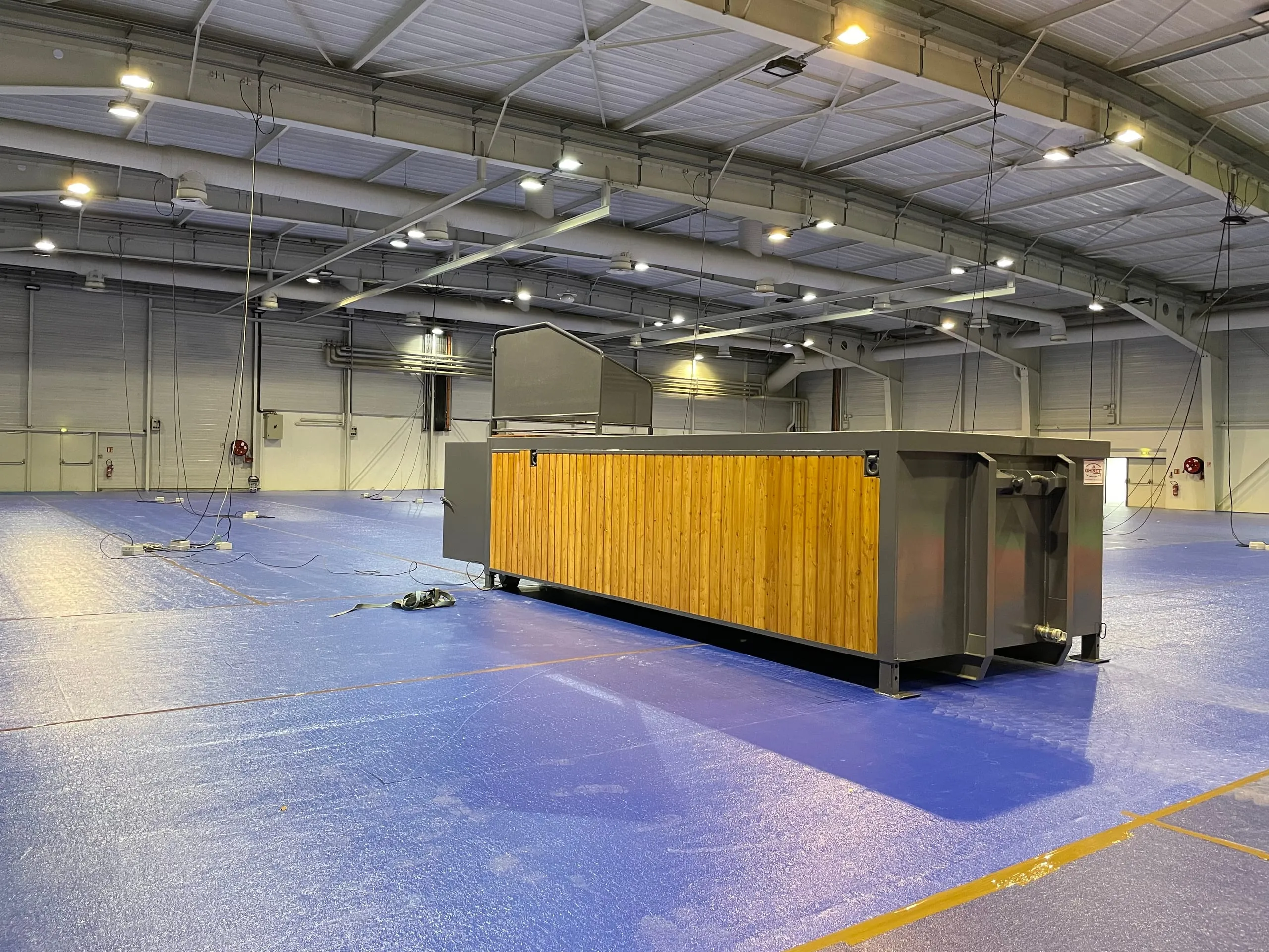 Vue trois quarts de la piscine container mobile Trident Piscine installée dans une halle sportive